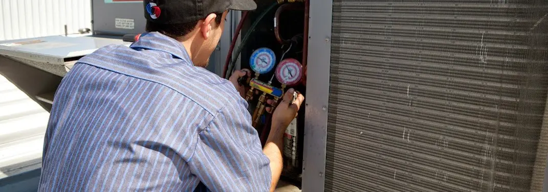 HVAC technician servicing a condenser unit in Roswell